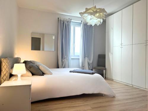 a bedroom with a large white bed and a chandelier at Duca - Gorizia City Apartment - 80 smq Central in Gorizia