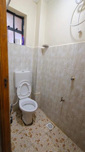 a bathroom with a toilet and a tiled floor at Coral Homes in Juja