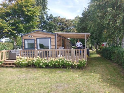 a man standing on the porch of a tiny house at Panorama Best View in Lauwersoog