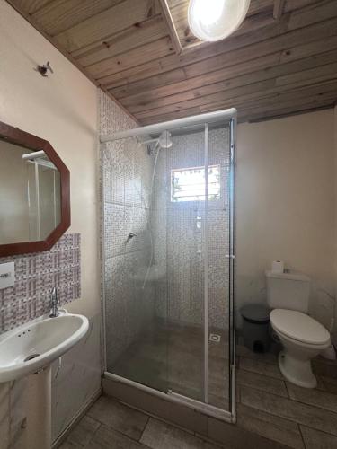 a bathroom with a shower and a toilet and a sink at Casa Vila Nova Alvorada in Imbituba