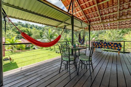 een veranda met een hangmat en een tafel en stoelen bij Cabañas Retiro Del Rio in Guayabal
