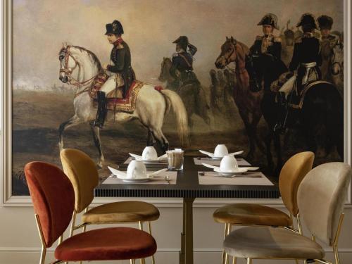 a dining room with a painting of soldiers on horses at Mercure Versailles Paris Ouest in Versailles