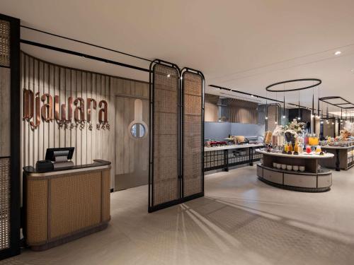 een restaurantlobby met een buffetlijn op de achtergrond bij Mercure Madiun in Madiun