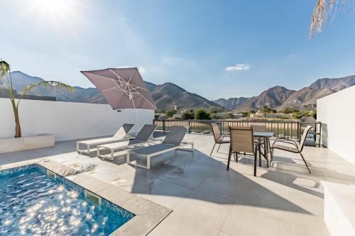a patio with a pool and chairs and an umbrella at Al Dana Paradise Luxury Villas Palm Fujairah Sea View in Fujairah
