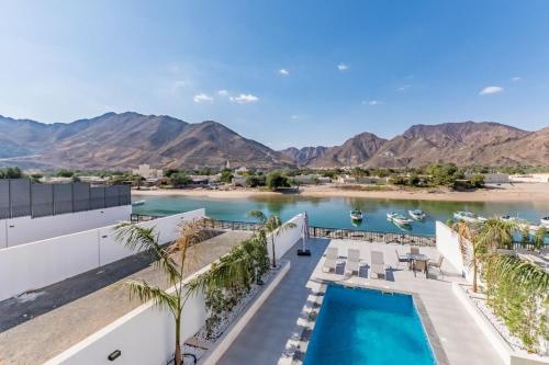a view of a resort with a pool and mountains at Al Dana Paradise Luxury Villas Palm Fujairah Sea View in Fujairah