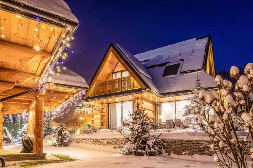 a log cabin in the snow with christmas lights at Luxury Chalet Wioska Jagny in Poronin