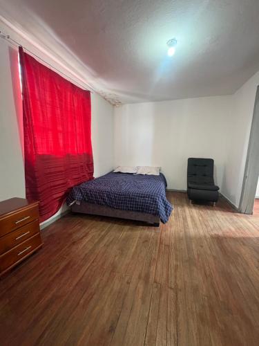 a bedroom with a bed and a red curtain at Hostal Los Robles in Pasto
