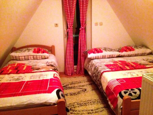 a bedroom with two beds and curtains in a attic at Kuća za odmor Vukas in Kupres