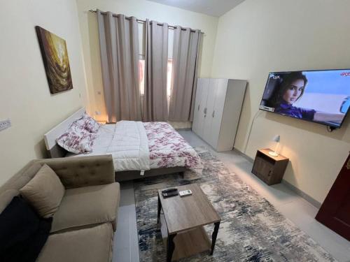 a living room with a couch and a flat screen tv at Cyclone Studio Apartments in Abu Dhabi