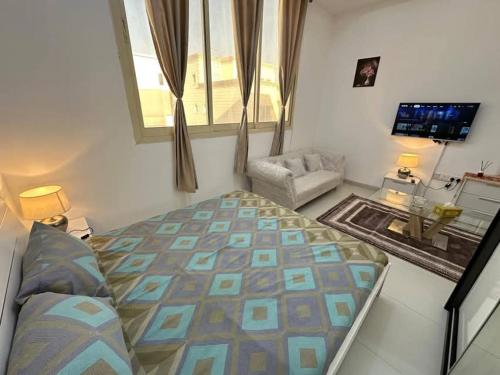 Una habitación con una cama, un sofá y un televisor. en Cyclone Studio Apartments, en Abu Dabi
