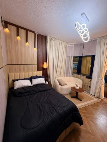 Un dormitorio con una cama negra y una silla. en Cyclone Studio Apartments, en Abu Dabi