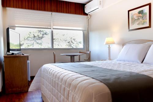a bedroom with a bed and a window and a television at Salto Grande Hotel in Punta del Este