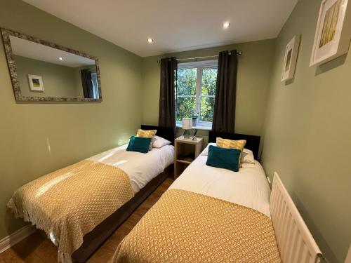 twee bedden in een kamer met een spiegel en een raam bij GF flat sleeps 4, parking for Contractors by Eagle Owl Stays in Crawley