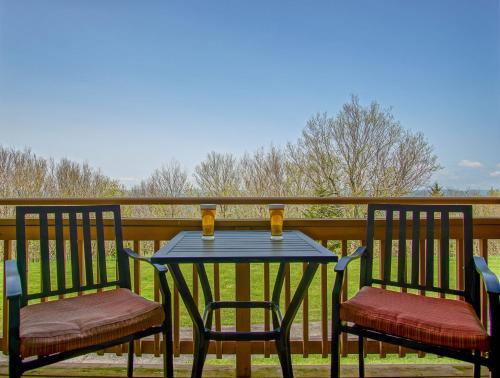 a table with two chairs and two drinks on a porch at Summit 107B 3Br Condo in Snowshoe
