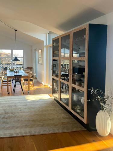 a kitchen and dining room with a large glass cabinet at Architect-Designed House With Private Beach in Løgstrup