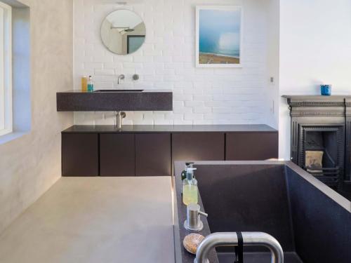 a bathroom with a black sink and a fireplace at Bredy Cottages in Bridport