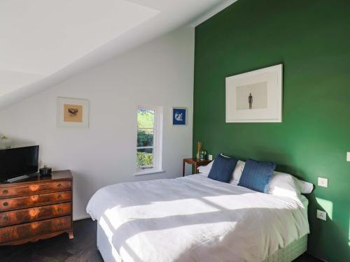 a bedroom with a bed and a green wall at Bredy Cottages in Bridport