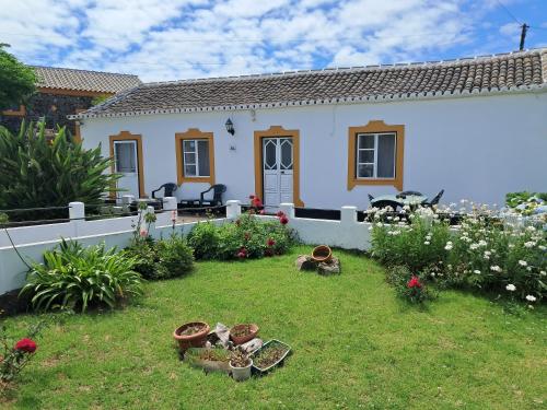 a white house with a yard with flowers and plants at Casa de Santa Catarina in Cabo da Praia