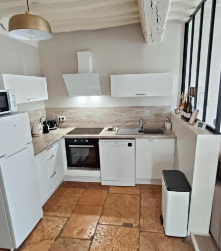 a kitchen with white cabinets and a sink at Le gîte de Varanges in Givry