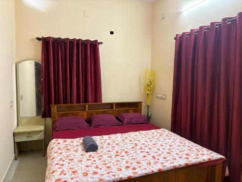 a bedroom with a bed with red drapes at SM Cottage in Mangalore