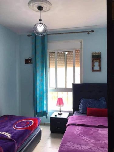a bedroom with a purple bed and a window at Sweet appartement in Tangier