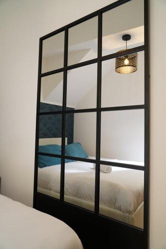 a mirror reflecting a bed in a room at Le Patio Spa in Chartres