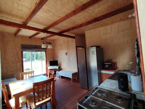 een keuken en eetkamer met een koelkast en een tafel bij Cabaña el Maitén Ensenada in Puerto Varas
