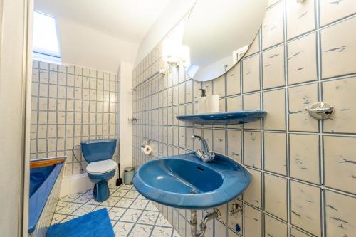 a bathroom with a blue sink and a toilet at Hotel Mutter Buermann Hannover in Hemmingen