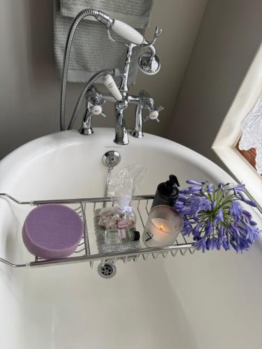 a bath tub with a glass shelf in a sink at GRACE COTTAGE Charming 2 Bed en-suite Cottage with Solar in Cape Town