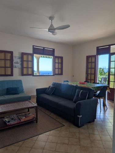 Una sala de estar con un sofá azul y una mesa. en Location Hibiscus, en Pointe-Noire