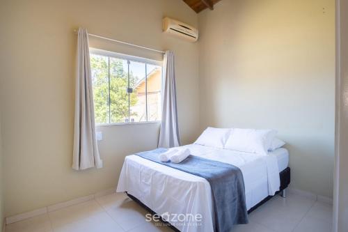 a bedroom with a bed and a window at 2-Bedroom House with Barbecue Area WIL0012 in Imbituba