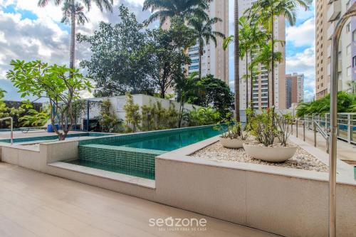 a swimming pool in a building with palm trees at Charmosos Flats no Setor Bueno TXP in Goiânia