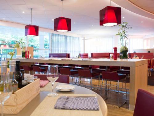 a restaurant with a bar with chairs and red chandeliers at Novotel Rotterdam Brainpark in Rotterdam
