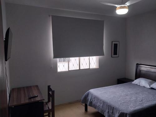a bedroom with a bed and a window and a table at Casa charmosa com vista e lazer in Belo Horizonte