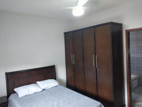 a bedroom with a bed and a wooden cabinet at Casa charmosa com vista e lazer in Belo Horizonte