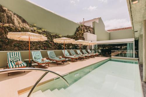 a swimming pool with lounge chairs and umbrellas at Torel Terra Brava in Angra do Heroísmo