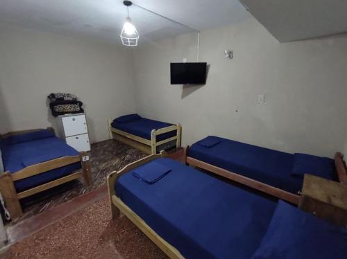 a room with three beds and a tv in it at Como en casa Hostel in Posadas