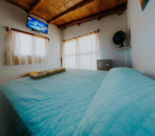 a large blue bed in a room with a tv at Bungalows Sol y Mar in Canoas de Punta Sal