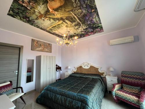 een slaapkamer met een bed en een schilderij aan het plafond bij Villa GIOBEA in Favara
