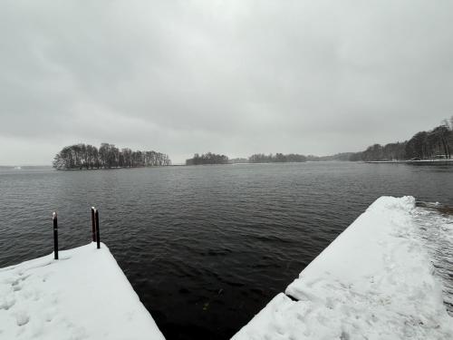 a dock covered in snow next to a body of water at Mazurski Apartament in Dadaj
