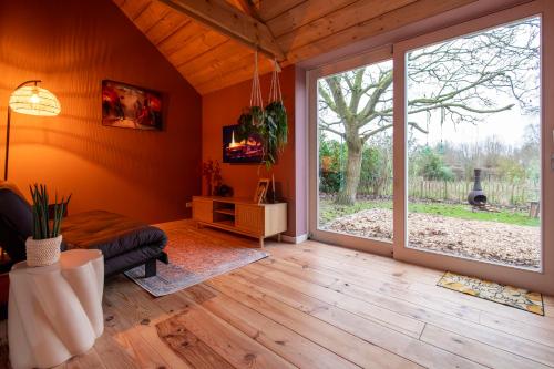 a living room with a large sliding glass door at Houten huisje met keuken en tuin in Halsteren, Bergen op Zoom in Halsteren