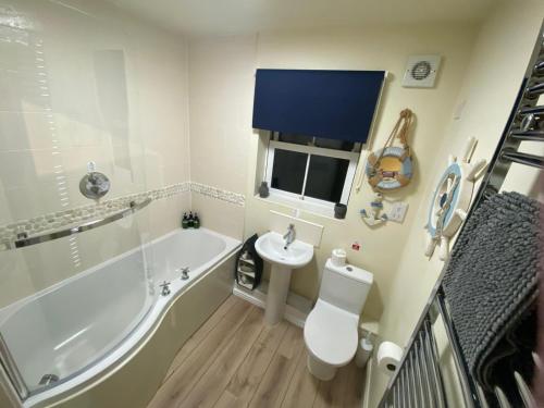 a bathroom with a tub and a toilet and a sink at Seaglass, The Bay - Filey Ground Floor Step Free Easy Access and Parking in Filey