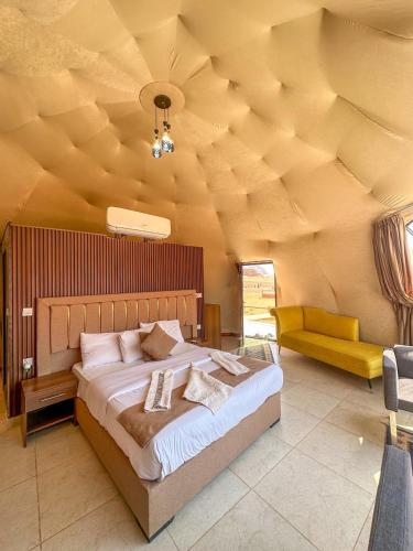 a bedroom with a large bed and a yellow couch at RUM ARIZONA lUXURY CAMP in Wadi Rum