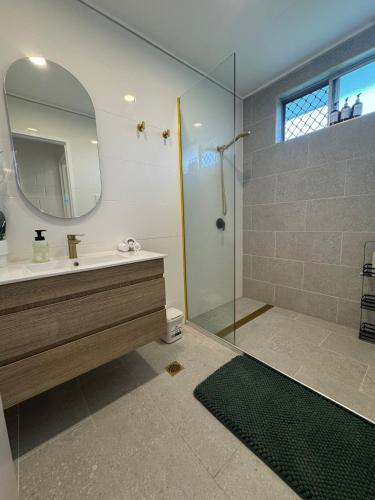 a bathroom with a sink and a shower with a mirror at Large Earthy toned Apartment in Ross River