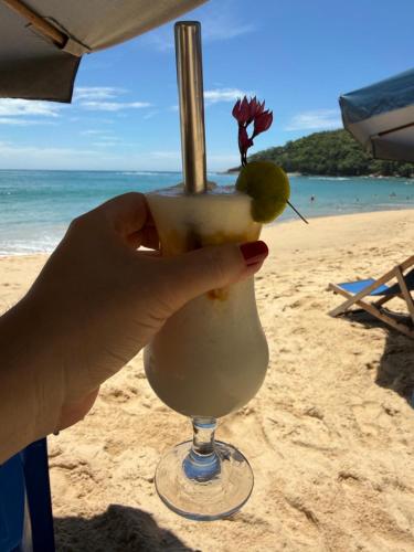 eine Hand, die einen Drink am Strand hält in der Unterkunft Flat Trindade in Trindade