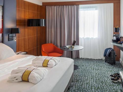 ein Hotelzimmer mit einem Bett, einem Stuhl und einem Tisch in der Unterkunft Hotel Mercure Toulouse Centre Compans in Toulouse