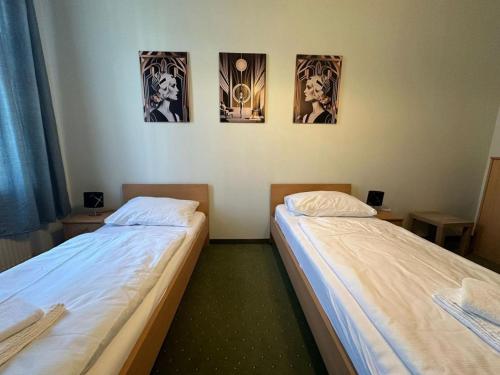 two beds in a room with three pictures on the wall at Mariazellerhof Suite 016 in Sankt Pölten