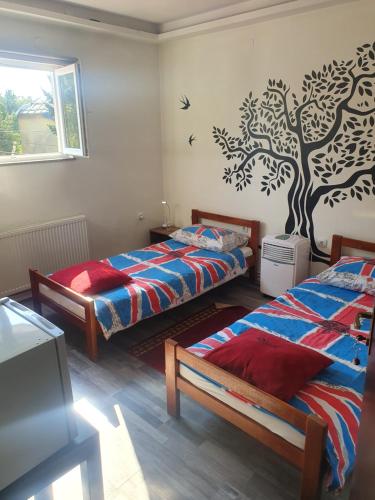 een slaapkamer met 2 bedden en een muurschildering van bomen aan de muur bij Hostel IN Club in Zagreb