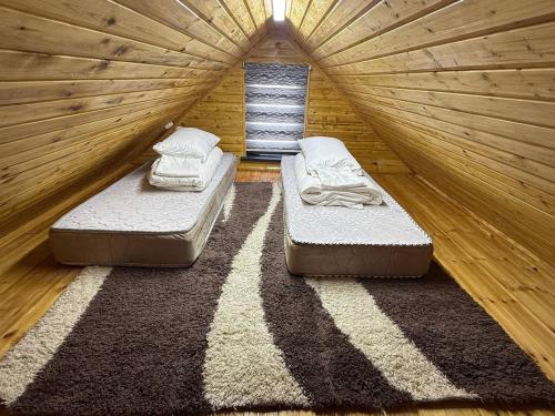 una stanza con due letti in una stanza di legno di Aura BarnHouse a Karakol