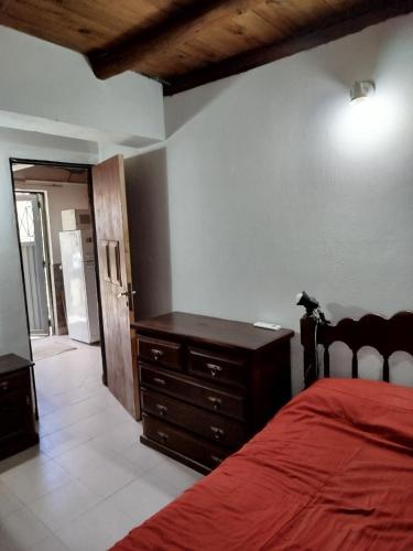 a bedroom with a red bed and a wooden dresser at Santa Mónica in Villa Giardino